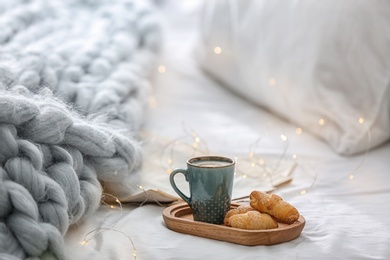 Cup of coffee and croissants on bed at home