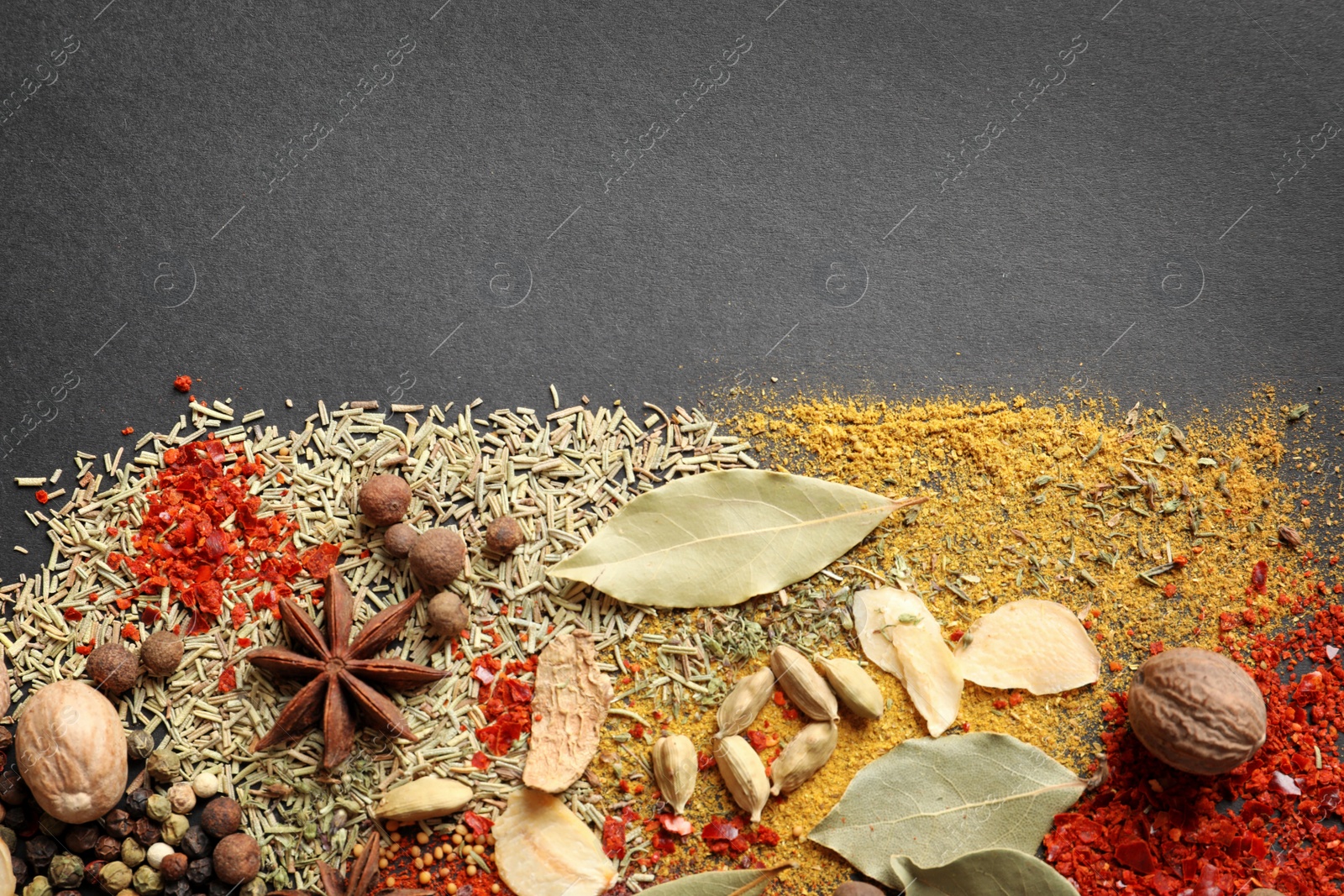 Photo of Different aromatic spices on dark background, top view with space for text