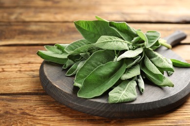 Photo of Bunch of fresh sage leaves on wooden table, closeup