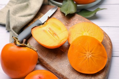 Photo of Delicious ripe juicy persimmons on wooden board, closeup