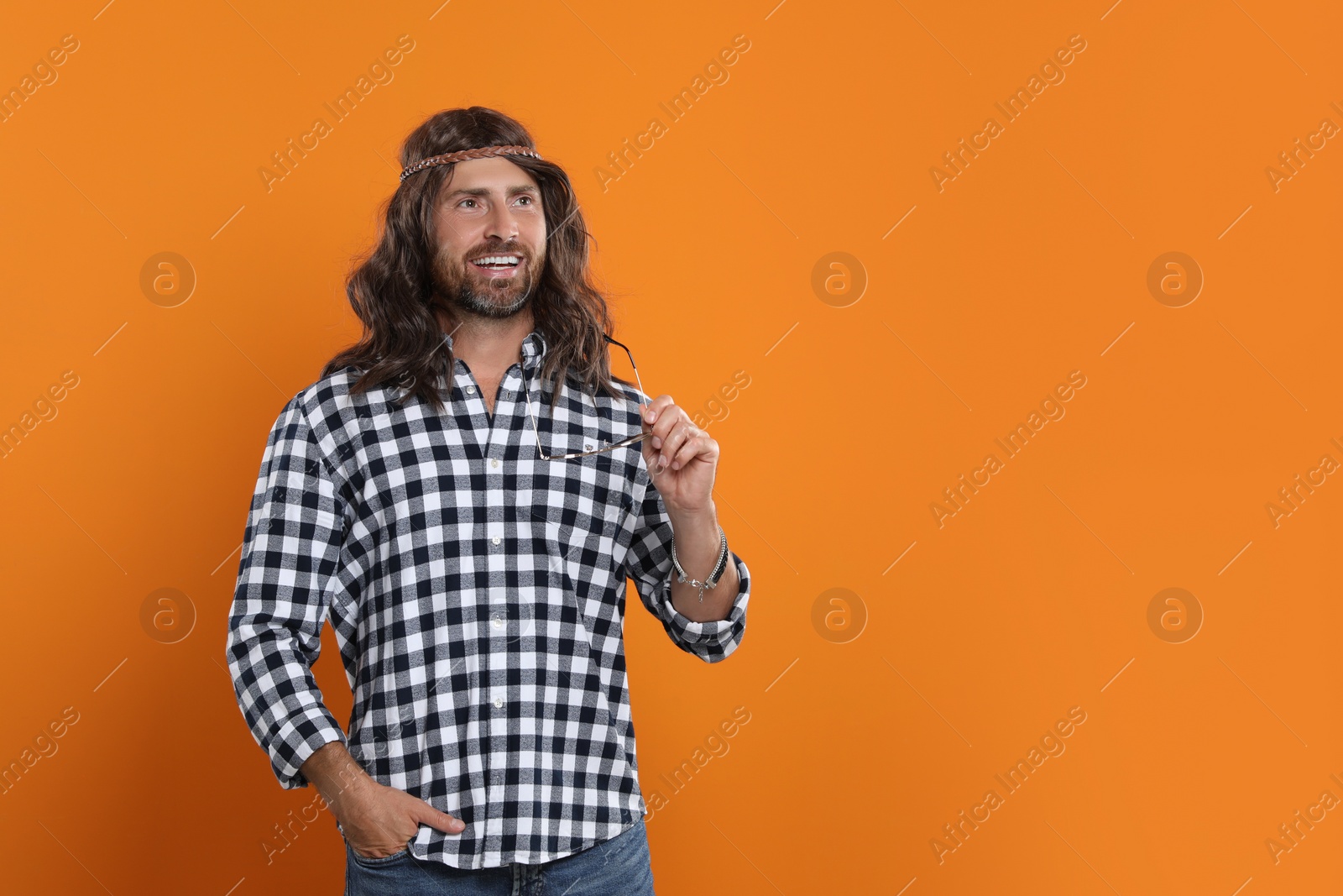 Photo of Hippie man with sunglasses on orange background, space for text