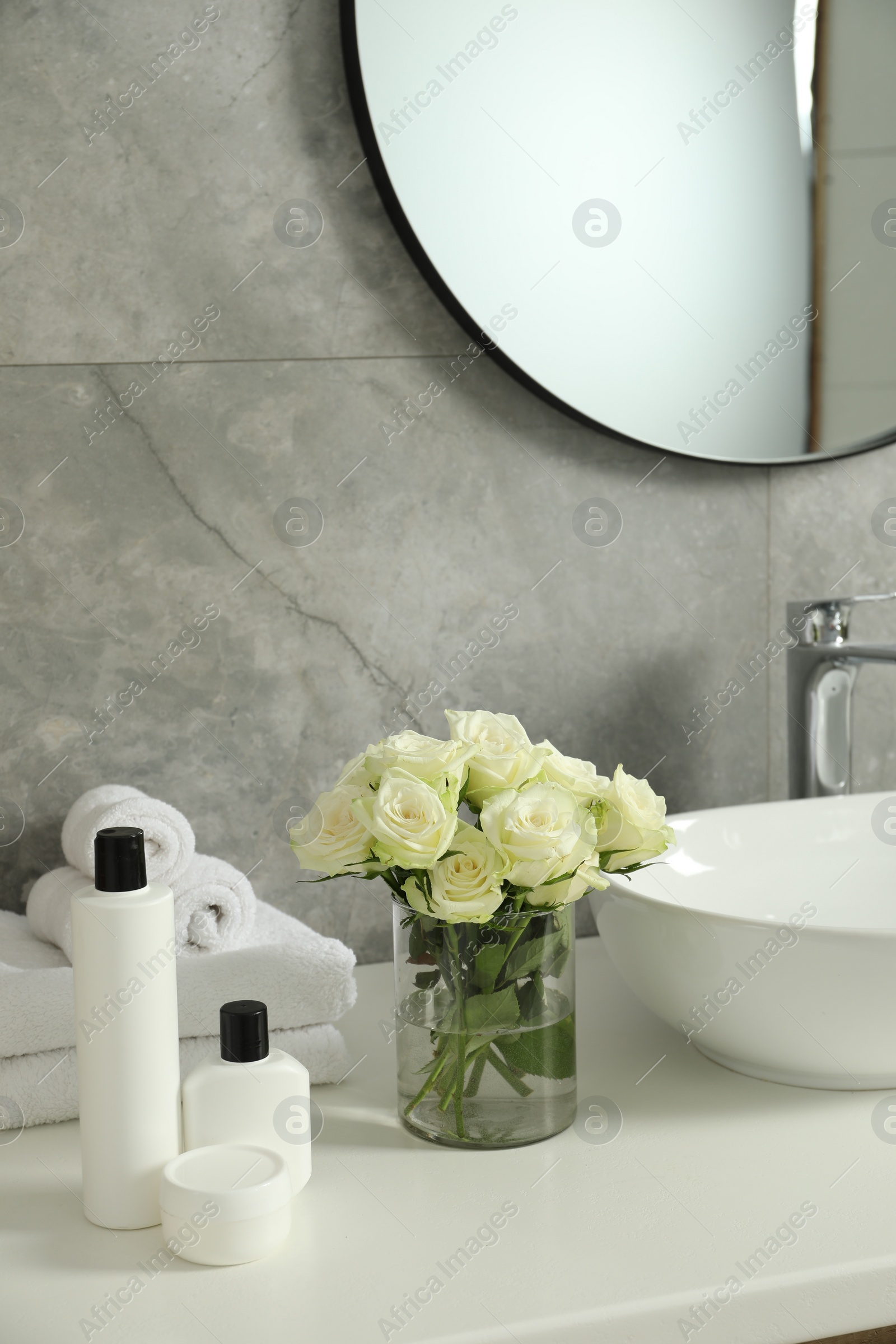 Photo of Beautiful roses and bath accessories near sink in bathroom