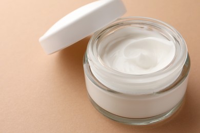 Photo of Jar of face cream on beige background, closeup