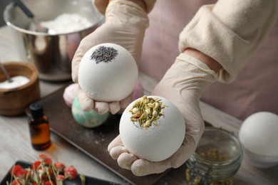 Photo of Woman in gloves with self made bath bombs at table, closeup