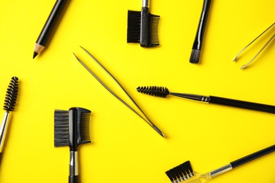 Photo of Set of professional eyebrow tools on yellow background, flat lay