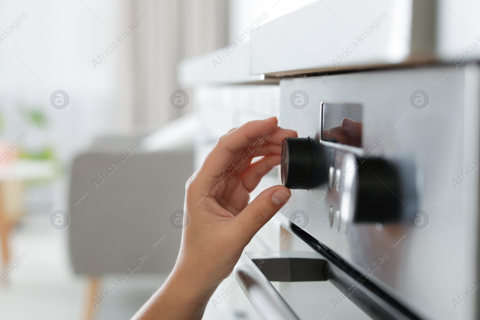 Photo of Woman regulating cooking mode on oven panel, closeup