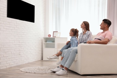 Photo of Happy family watching TV on sofa at home