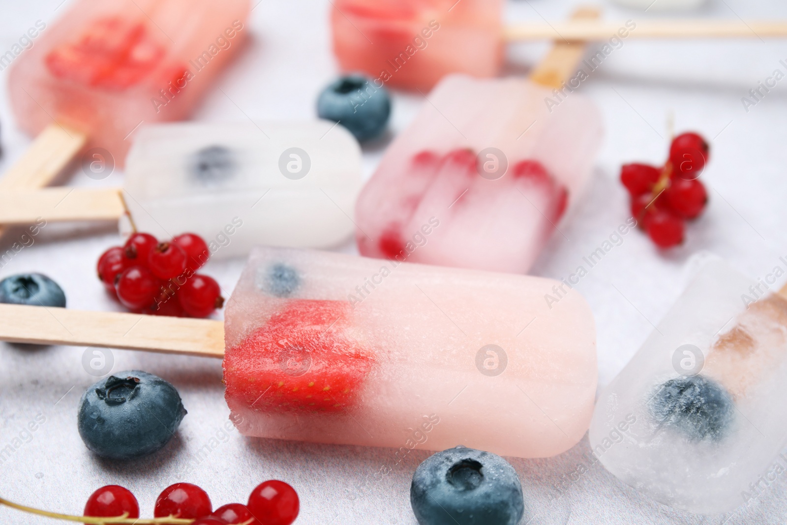 Photo of Tasty berry ice pops on light table, closeup