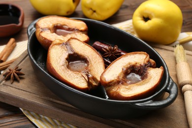 Tasty baked quinces with spices and honey in dish on table, closeup