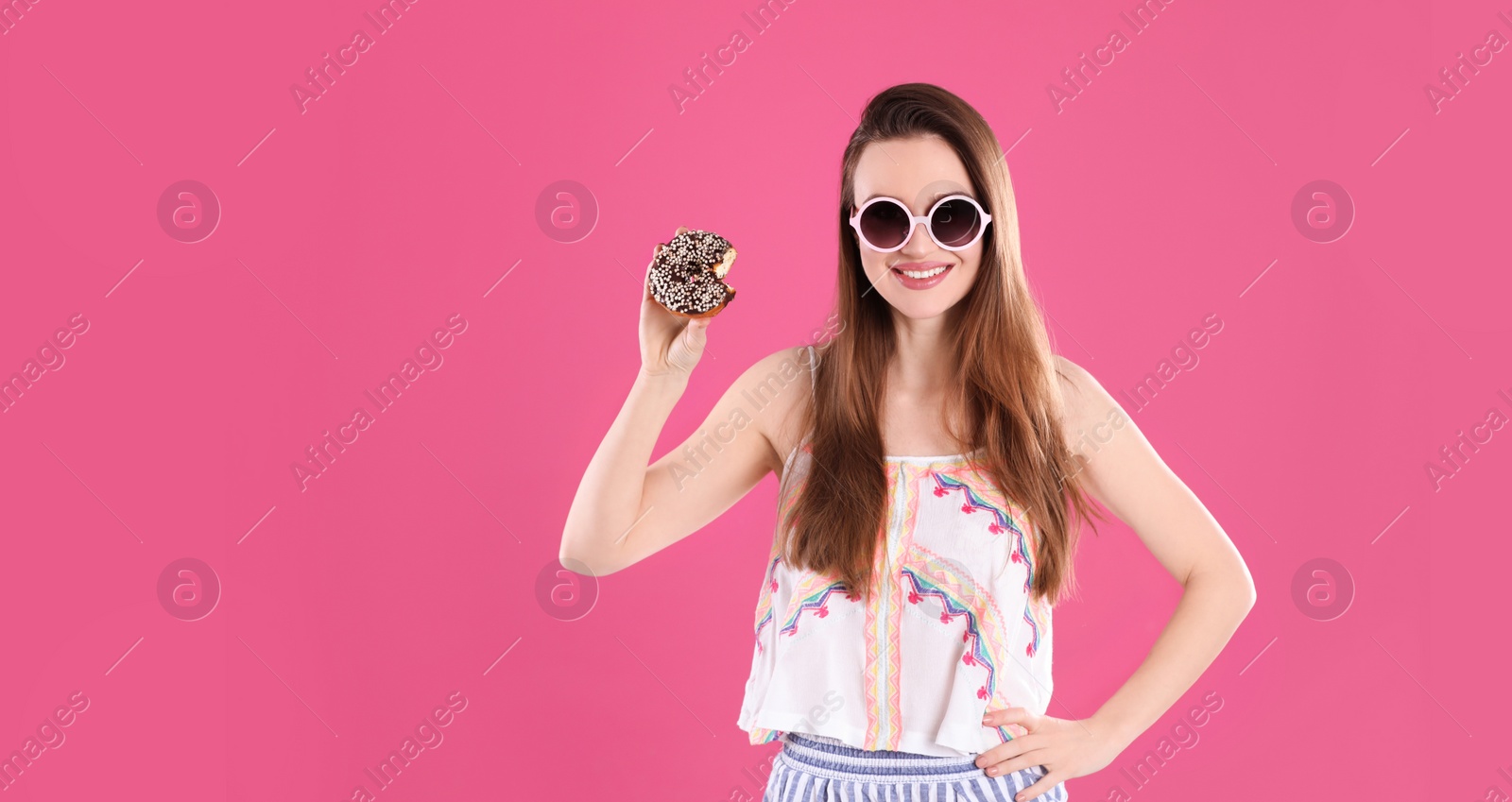 Photo of Beautiful young woman wearing sunglasses with donut on pink background