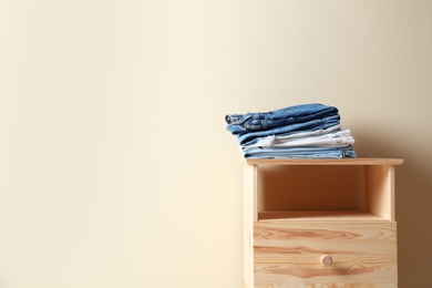 Photo of Stack of different jeans on table against color background