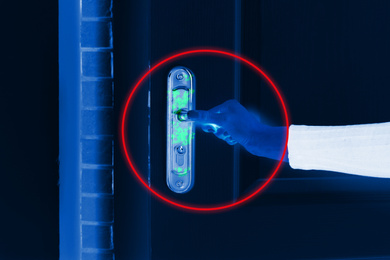 Image of Woman opening door, closeup view under UV light. Avoid touching surfaces in public spaces during coronavirus outbreak