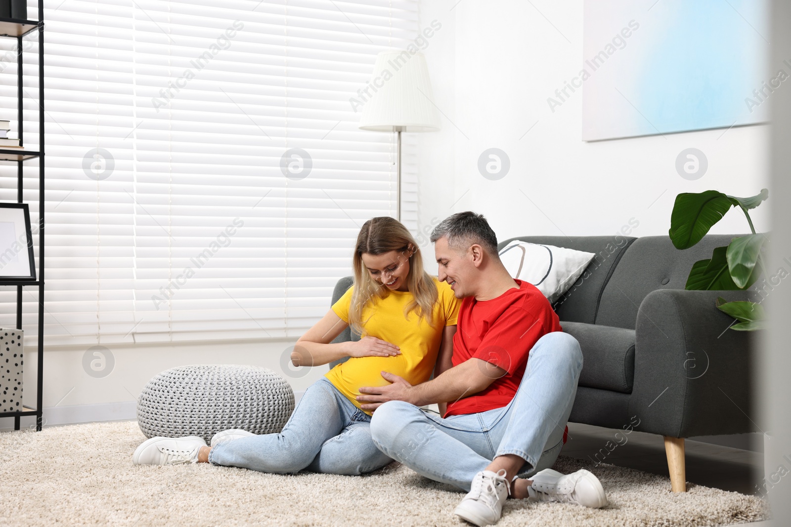 Photo of Young family housing concept. Pregnant woman with her husband on floor at home