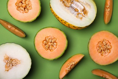 Photo of Cut different types of melons on green background, flat lay