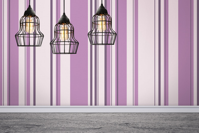 Image of Stylish pendant lamps hanging near striped wall in room