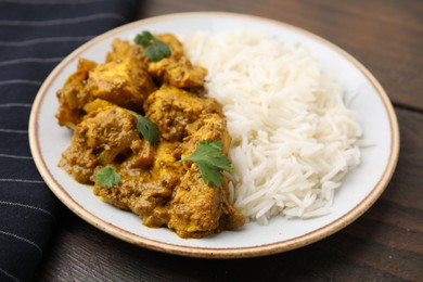 Photo of Delicious chicken curry with rice on wooden table, closeup