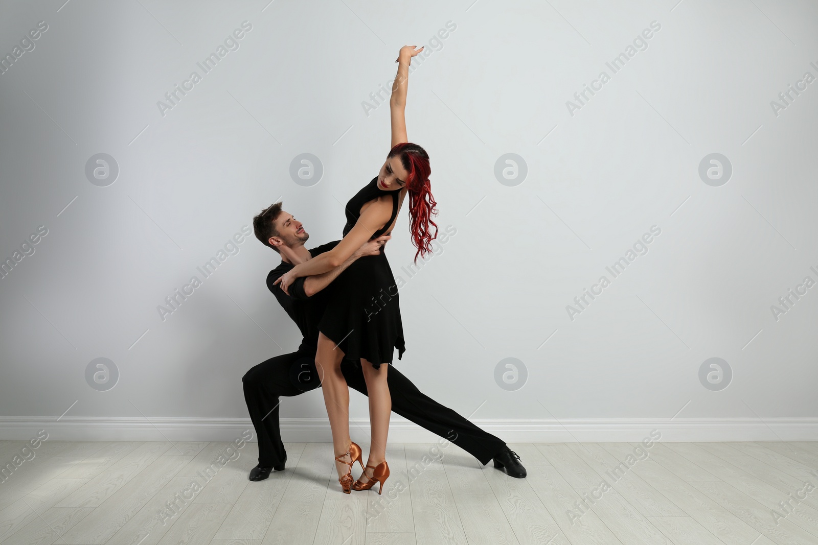 Photo of Beautiful young couple dancing near light wall