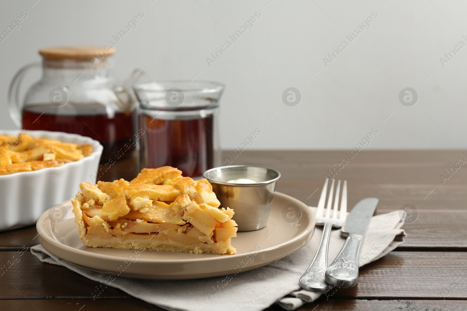 Photo of Piece of tasty homemade quince pie with ice cream on wooden table, closeup. Space for text