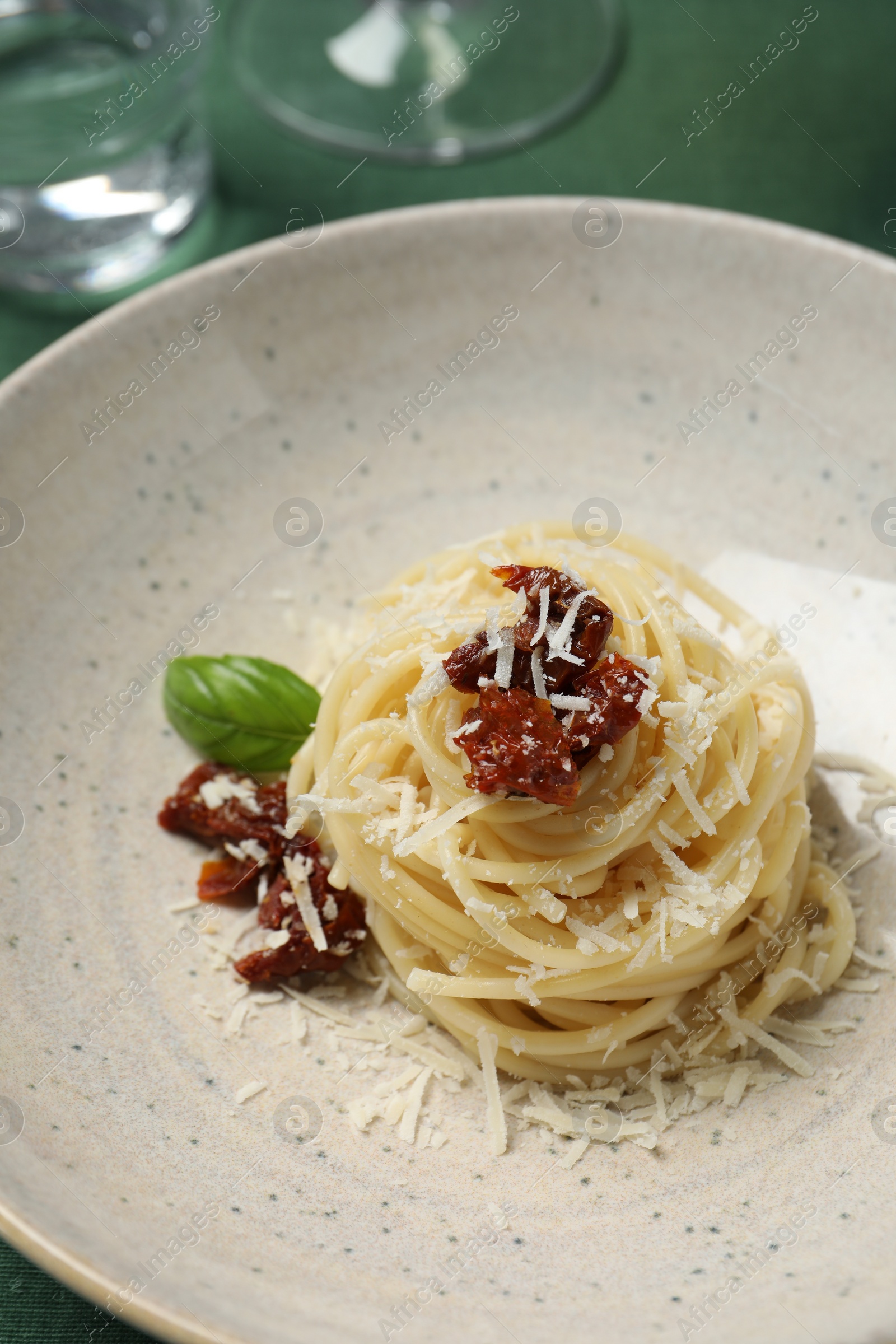 Photo of Tasty spaghetti with sun-dried tomatoes and parmesan cheese on plate, closeup. Exquisite presentation of pasta dish