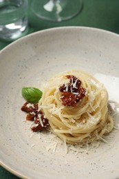 Photo of Tasty spaghetti with sun-dried tomatoes and parmesan cheese on plate, closeup. Exquisite presentation of pasta dish