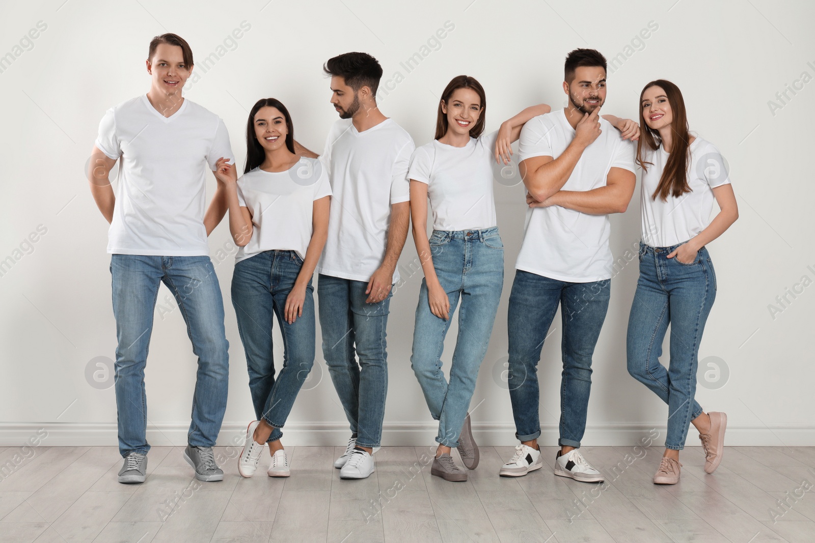 Photo of Group of young people in stylish jeans near white wall