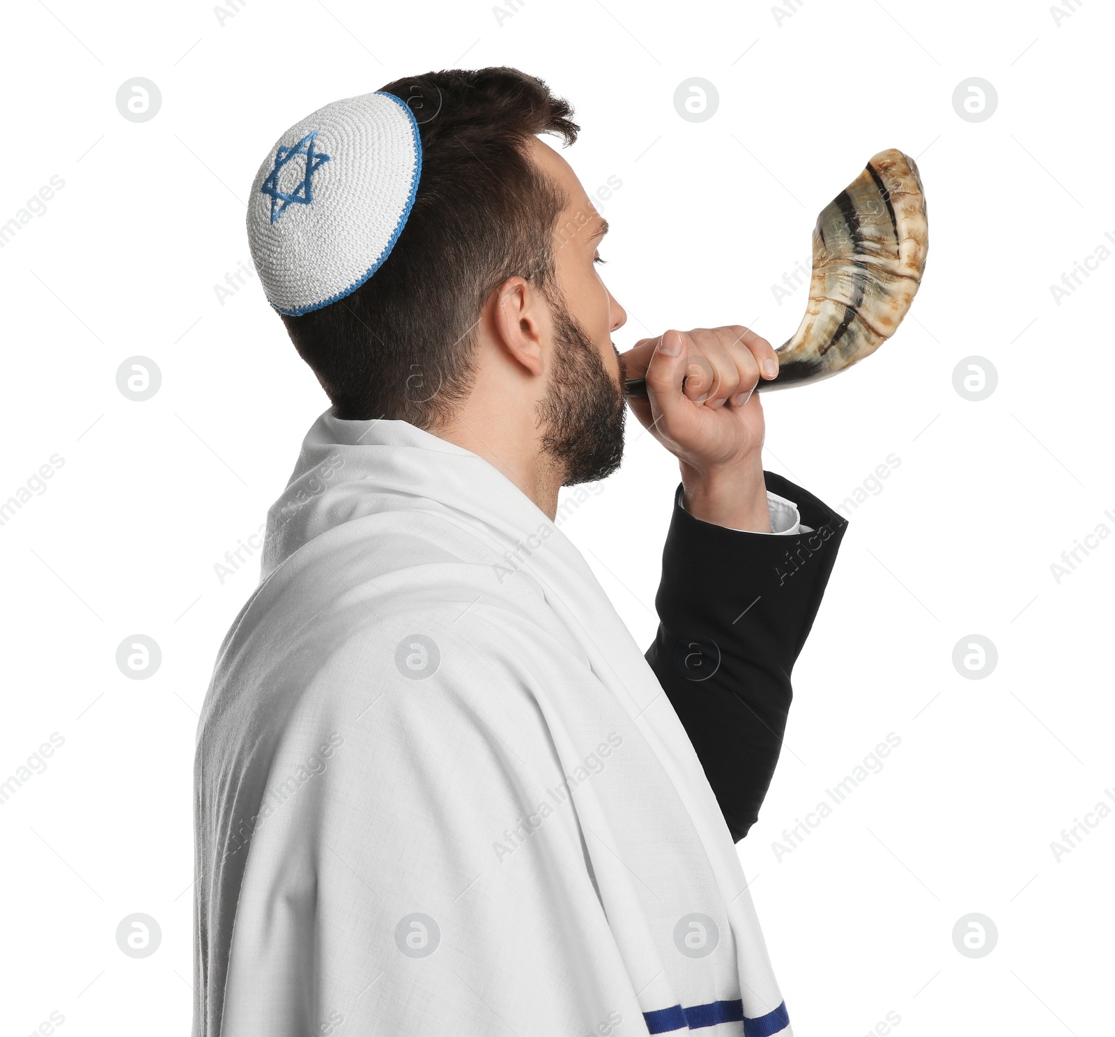 Photo of Jewish man with kippah and tallit blowing shofar on white background. Rosh Hashanah celebration