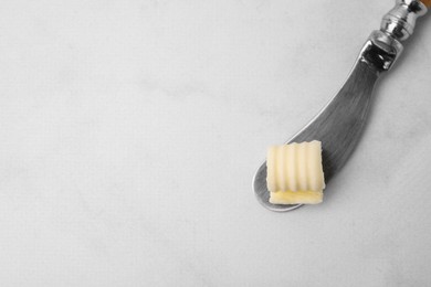 Photo of Tasty butter curl and knife on white table, top view. Space for text