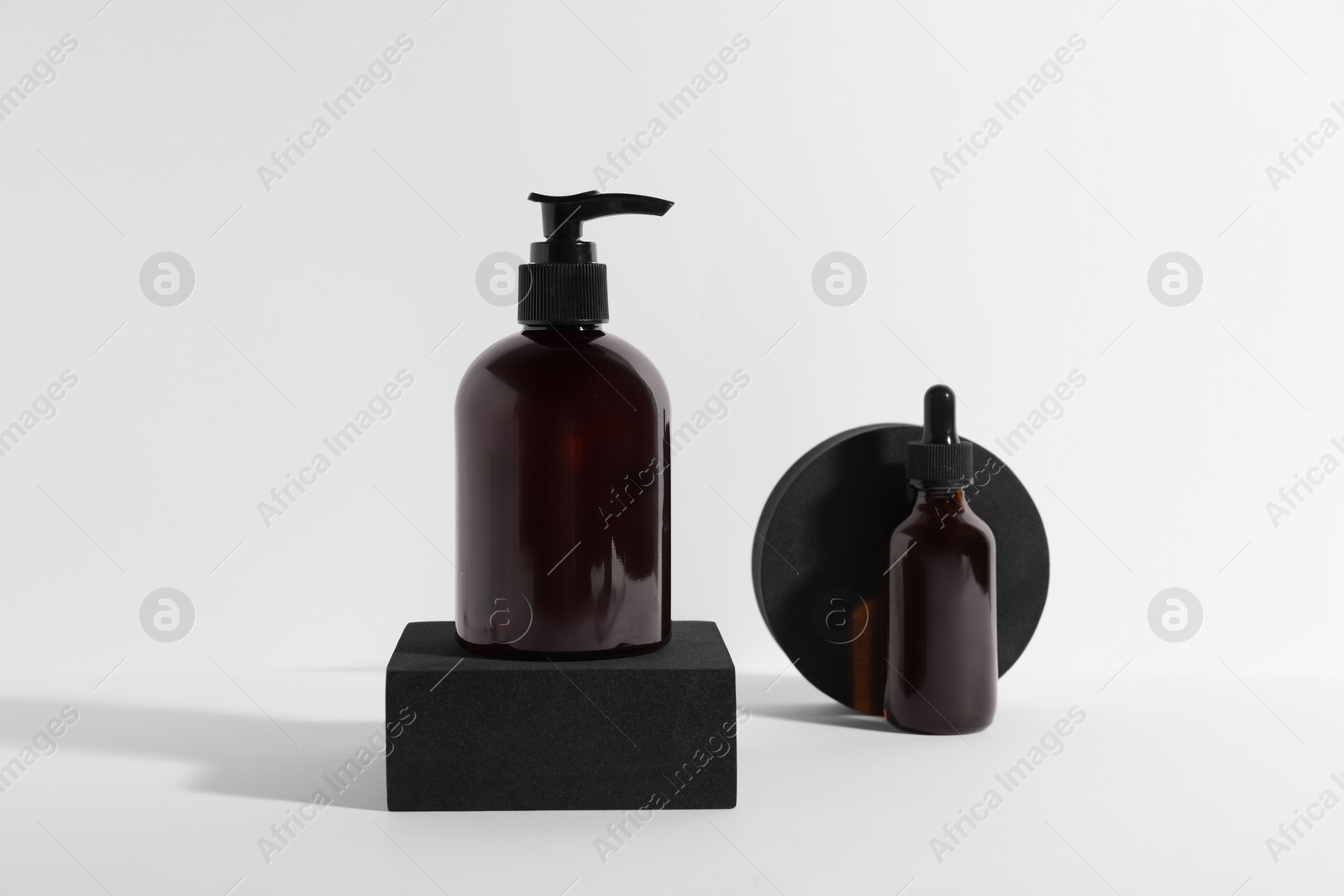 Photo of Bottles with different cosmetic products and podiums on white background