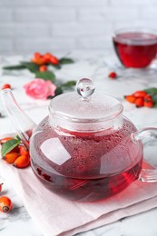 Photo of Fresh rose hip tea and berries on white marble table