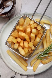 Photo of Tasty french fries with rosemary and soda drink on light grey table, flat lay