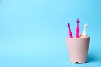 Baby toothbrushes in holder and space for text on color background