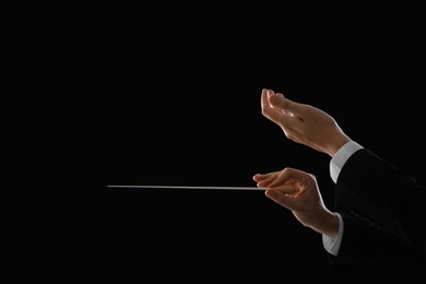 Photo of Professional conductor with baton on black background, closeup. Space for text