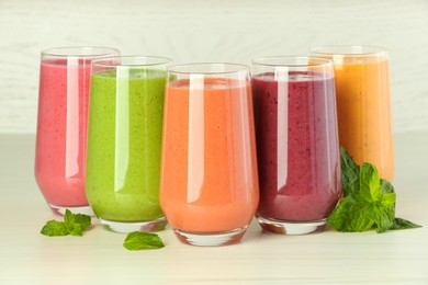 Photo of Colorful fruit smoothies and fresh mint on white wooden table
