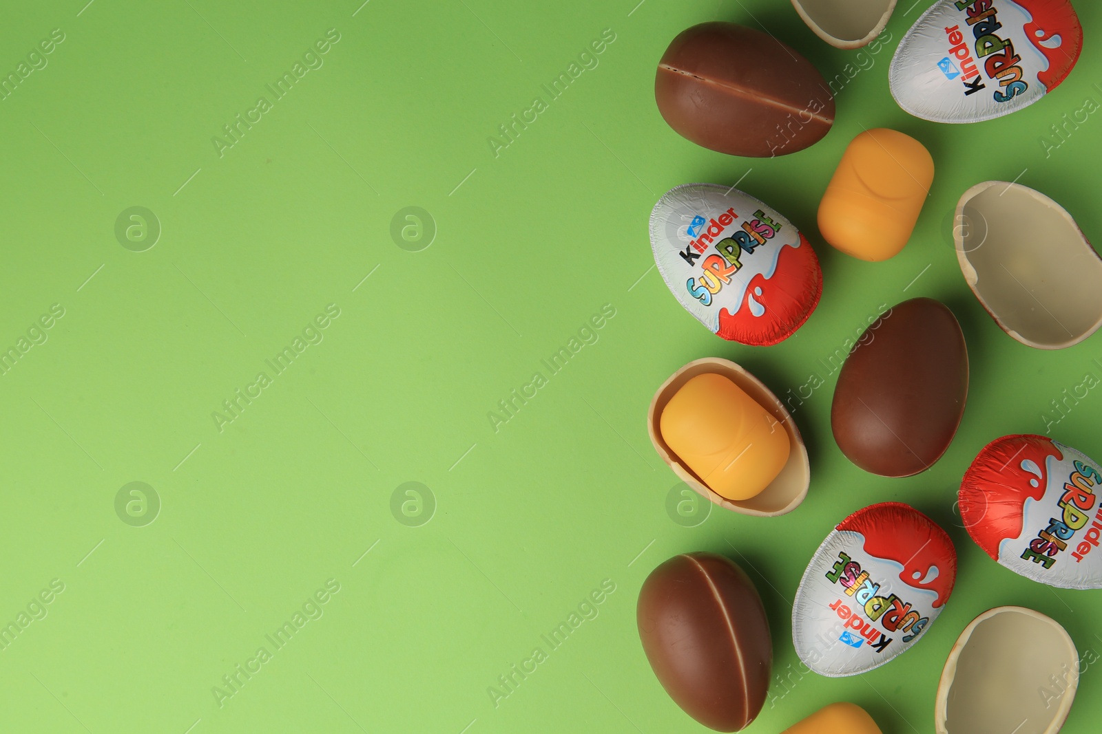 Photo of Sveti Vlas, Bulgaria - June 29, 2023: Kinder Surprise Eggs and plastic capsules on light green background, flat lay. Space for text