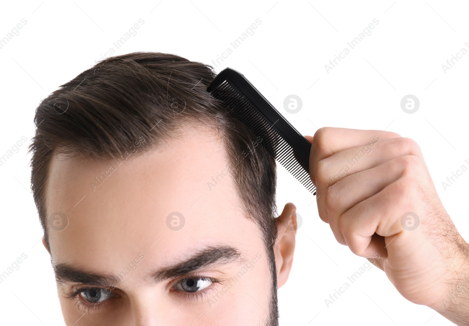 Photo of Young man with comb on white background, closeup. Hair loss problem