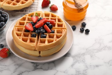 Photo of Tasty Belgian waffles with fresh berries and honey on white marble table, space for text