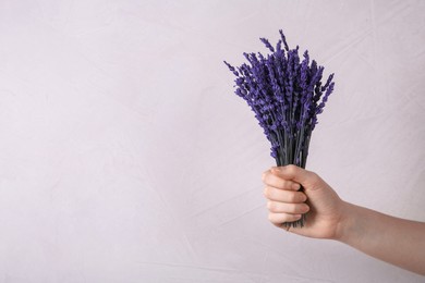 Photo of Woman holding bouquet of beautiful preserved lavender flowers on beige background, closeup. Space for text