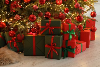 Many gift boxes under decorated Christmas tree indoors