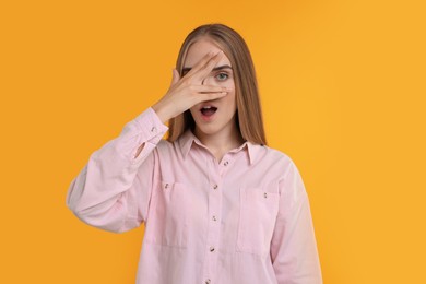 Photo of Embarrassed woman covering face with hand on orange background