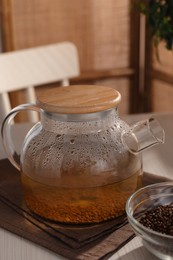 Glass teapot with aromatic buckwheat tea and granules on wooden table