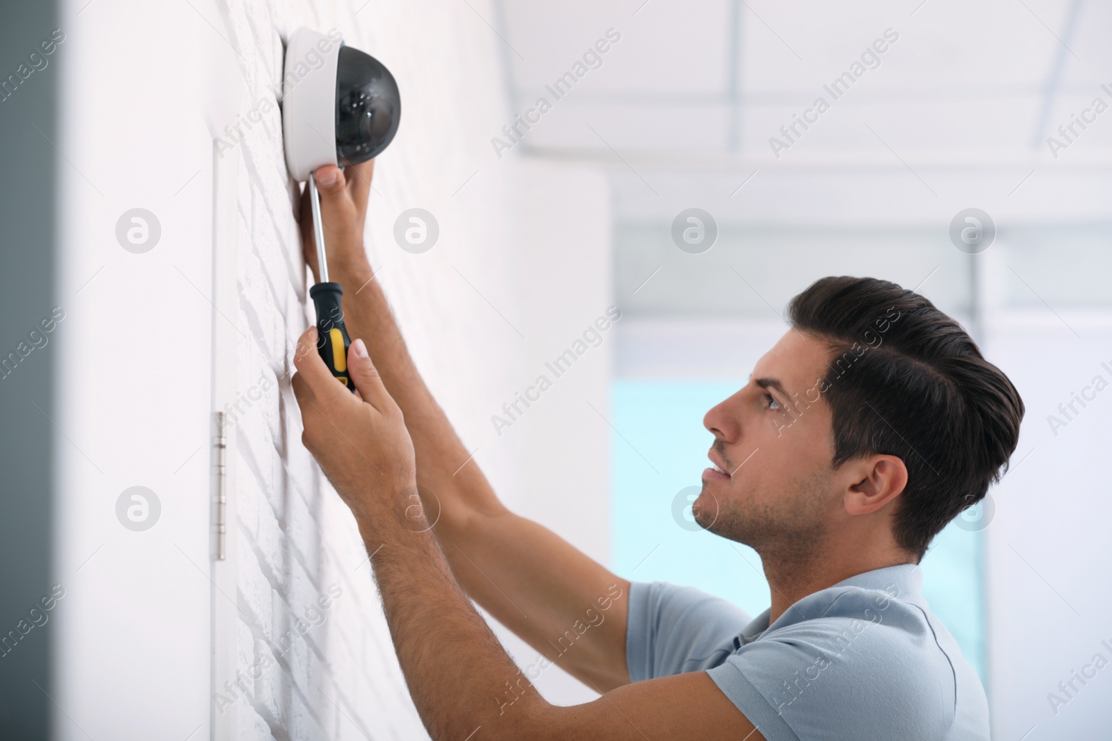 Photo of Technician installing CCTV camera on wall indoors