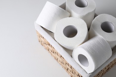 Photo of Toilet paper rolls in wicker basket on white table, space for text
