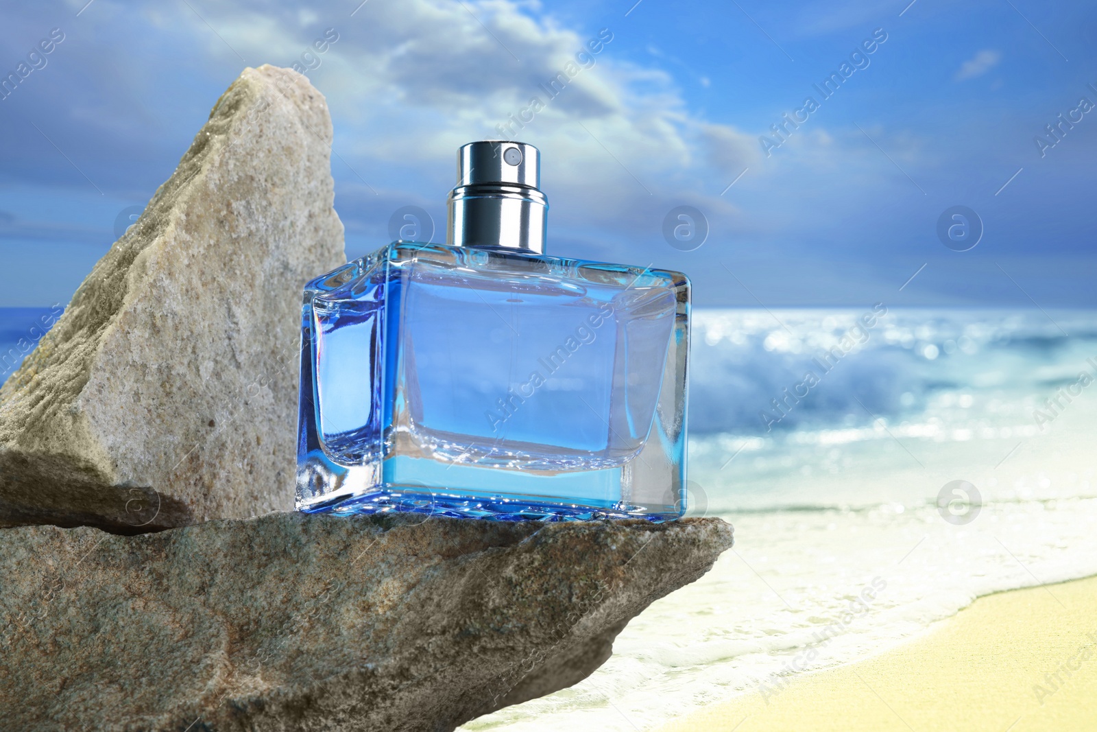 Image of Bottle of aquatic perfume on rock near ocean. Fresh sea breeze scent