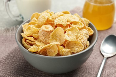 Photo of Bowl of sweet crispy corn flakes on kitchen towel, closeup. Breakfast cereal