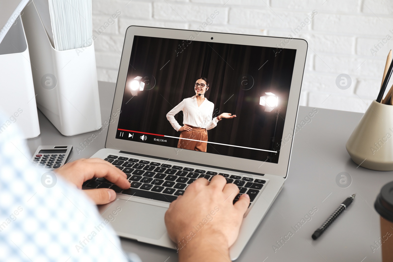 Image of Man watching performance of motivational speaker on laptop at grey table, closeup