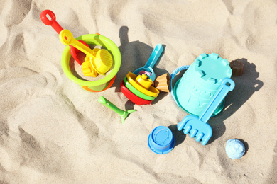 Different child plastic toys on sandy beach, above view