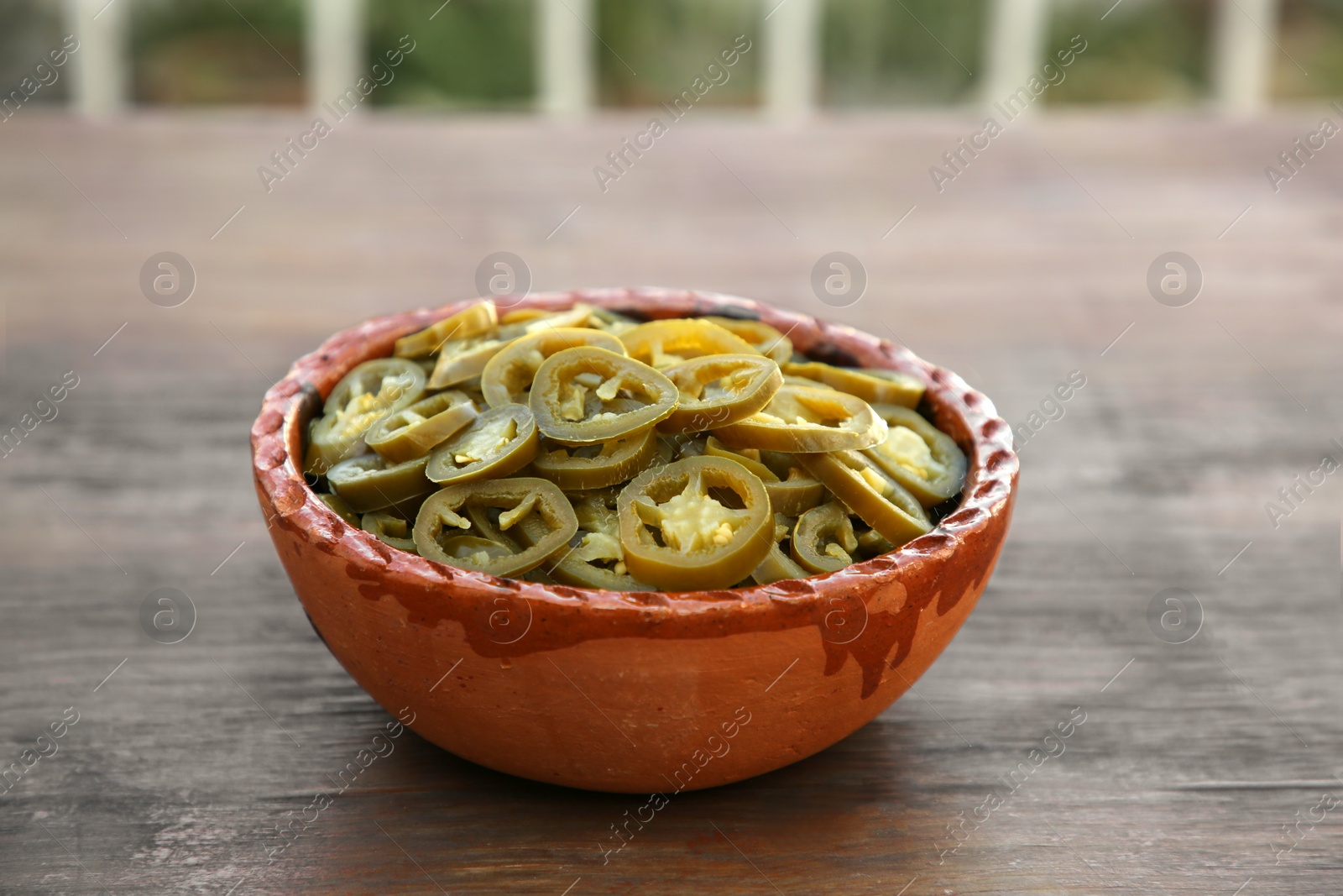 Photo of Pickled green jalapeno peppers on wooden table