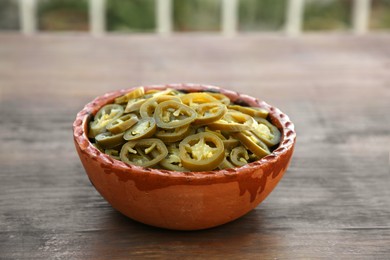 Photo of Pickled green jalapeno peppers on wooden table