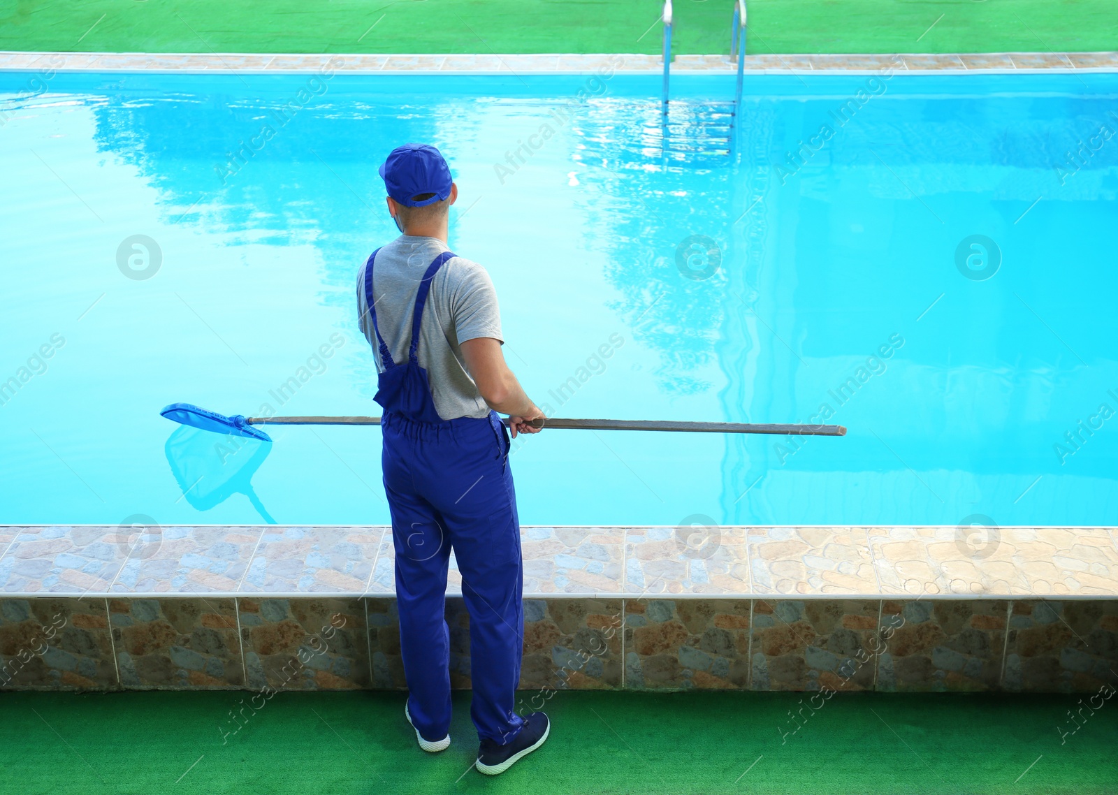 Photo of Male worker cleaning outdoor pool with scoop net