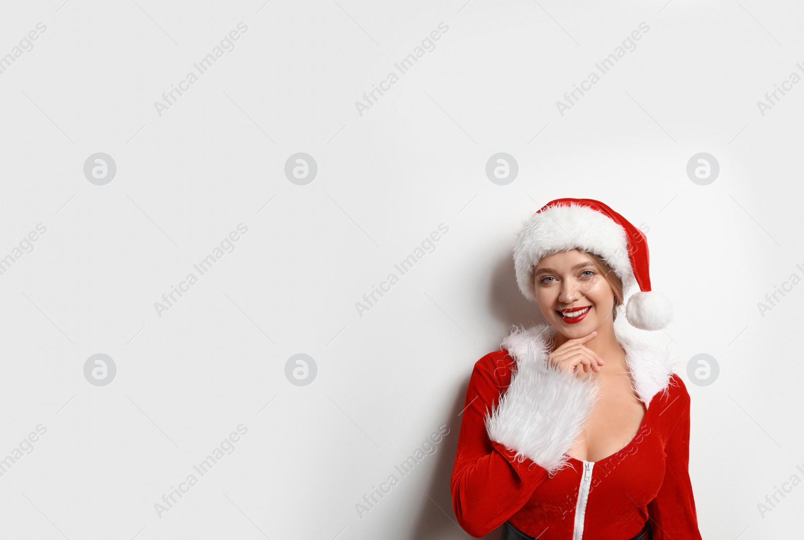 Photo of Beautiful Santa girl on light background, space for text. Christmas eve